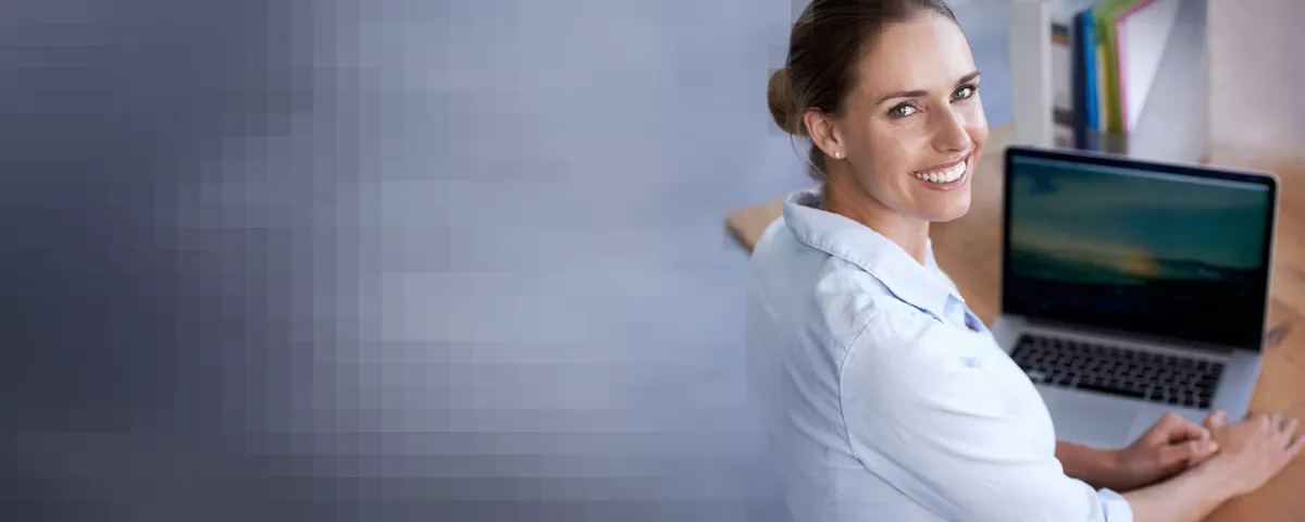 Lächelnde Frau am Notebook blickt nach rechts über die Schulter