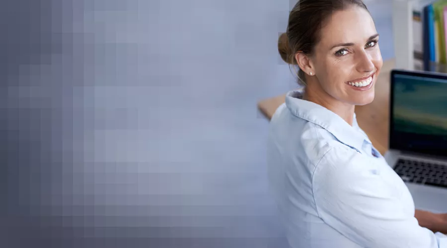 Lächelnde Frau am Notebook blickt nach rechts über die Schulter